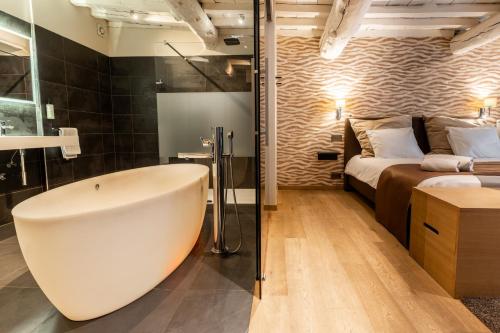a bathroom with a bath tub next to a bed at Hôtel Le Manoir in Marche-en-Famenne