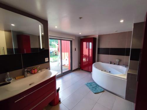 une salle de bain avec une baignoire et un grand miroir dans l'établissement Maison avec piscine et jardin proche mer, La Rochelle, à La Rochelle