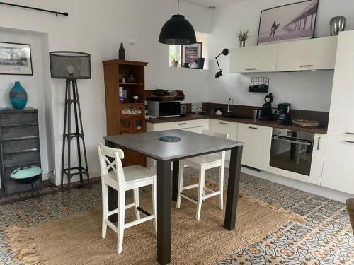 een keuken met een zwarte tafel en 2 witte stoelen bij TY MAI - petite maison proche plages et commerces in Trébeurden