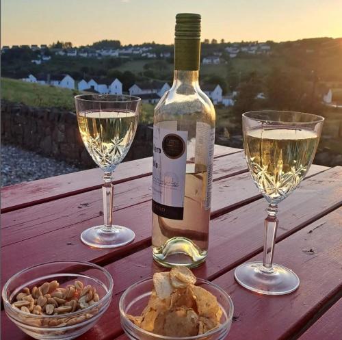een fles wijn en twee glazen op een houten tafel bij Red Gate Cottage in Buncrana