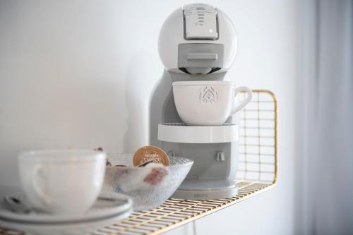 une cafetière assise sur une étagère avec des tasses dans l'établissement Palacete de La Alameda - Adults Only-, à Cadix