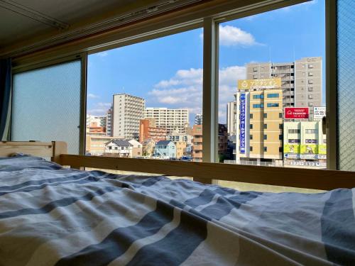 a bedroom with a view of a city from a window at Fukuoka Tabiji Hostel & Guesthouse in Fukuoka