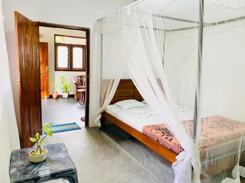 a bedroom with a bed with mosquito net at Surfing Waves Madiha in Matara