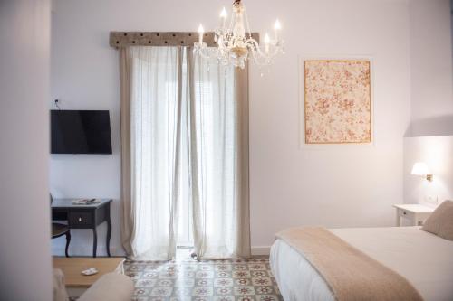 a bedroom with a bed and a chandelier at Palacete de La Alameda - Adults Only- in Cádiz