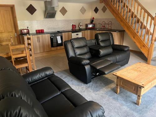 a living room with a black leather couch and a kitchen at Skegness Holiday Cottages in Skegness