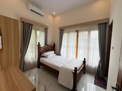 una camera con un letto e due grandi finestre di Vila Pandhappa a Kembanglimus