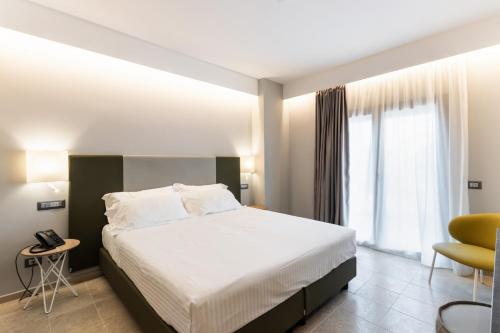 a bedroom with a large bed and a yellow chair at Hotel Netum Mare in Noto Marina