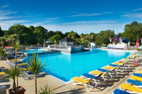 a large swimming pool with lounge chairs and a resort at Mobil-Home 3 Chambres, TOUT CONFORT, Option "DRAPS FOURNIS" Disponible ! in Pont-Aven