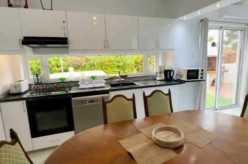 Una cocina con una mesa de madera y una cocina con gabinetes blancos. en Hotel complex house near the beach, en Pafos