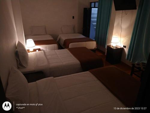 um quarto de hotel com duas camas e duas lâmpadas em Ortega's House Machupicchu em Machu Picchu