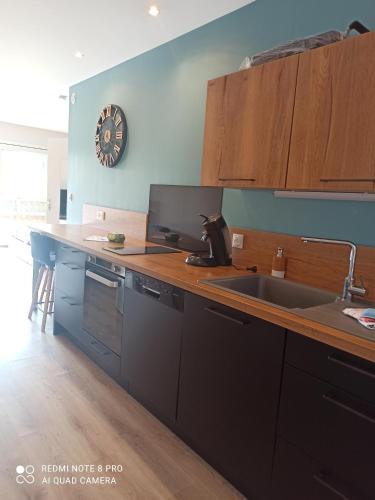 - une cuisine avec un comptoir, un évier et une horloge dans l'établissement LE DOUX REFUGE, à Orchaise
