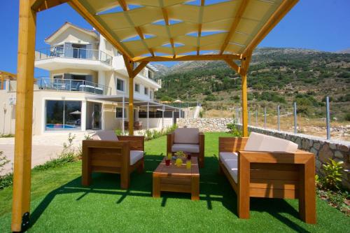 a patio with chairs and tables and a building at Kefalonia Horizon Villas in Ayia Evfimia