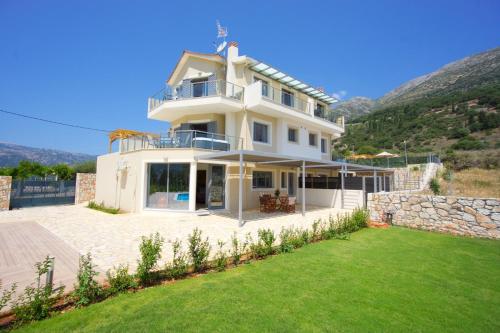 a large white house with a lawn in front of it at Kefalonia Horizon Villas in Ayia Evfimia