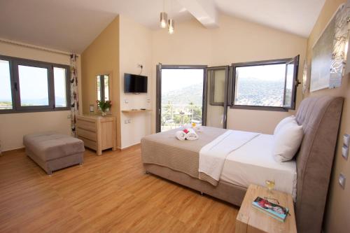 a bedroom with a bed and a tv and windows at Kefalonia Horizon Villas in Ayia Evfimia