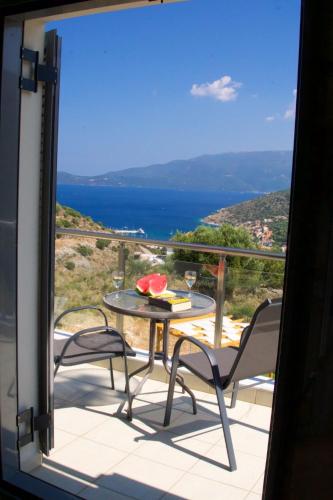 a balcony with a table and chairs and a view of the ocean at Kefalonia Horizon Villas in Ayia Evfimia