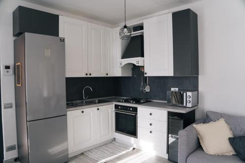 kuchnia z białymi szafkami i lodówką ze stali nierdzewnej w obiekcie COZY HOUSE Relax Wi-Fi & Design w mieście Colle Brianza