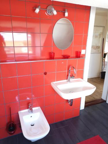 a red tiled bathroom with a sink and a mirror at Stranddüne in Cuxhaven
