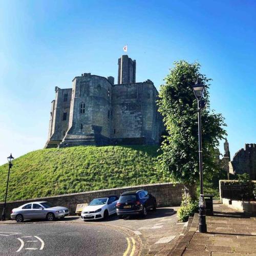 a castle with cars parked in a parking lot at The Hideaway - Luxury 2 bedroom ground floor apt in Warkworth