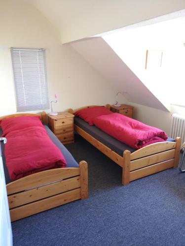 a bedroom with two twin beds with red sheets at Stranddüne in Cuxhaven