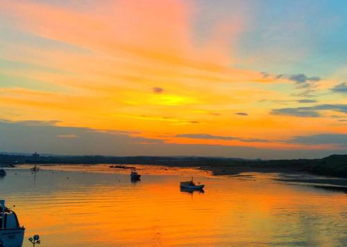 a sunset over a river with boats in the water at The Hideaway - Luxury 2 bedroom ground floor apt in Warkworth