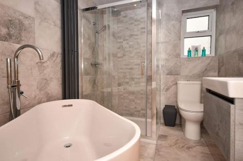 a bathroom with a tub and a toilet and a shower at The Hideaway - Luxury 2 bedroom ground floor apt in Warkworth