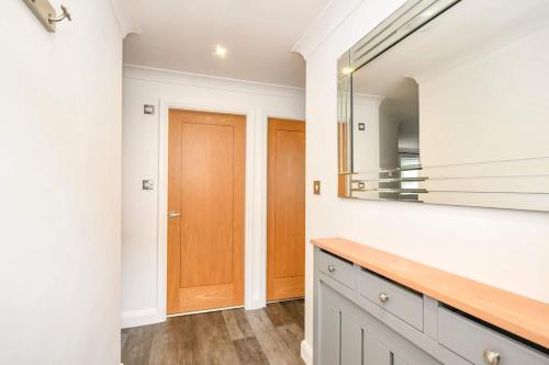 a bathroom with a mirror and a wooden door at The Hideaway - Luxury 2 bedroom ground floor apt in Warkworth