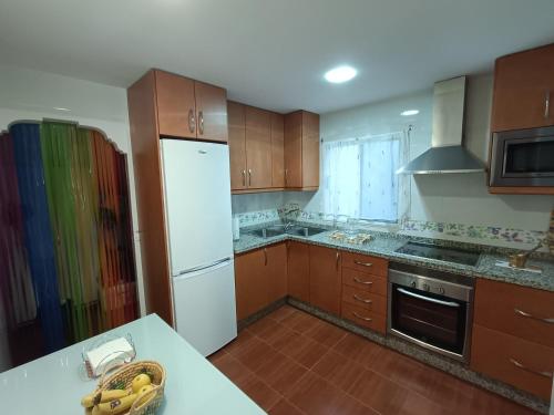 - une cuisine avec des placards en bois et un réfrigérateur blanc dans l'établissement Mi Carmela, à Cenes de la Vega