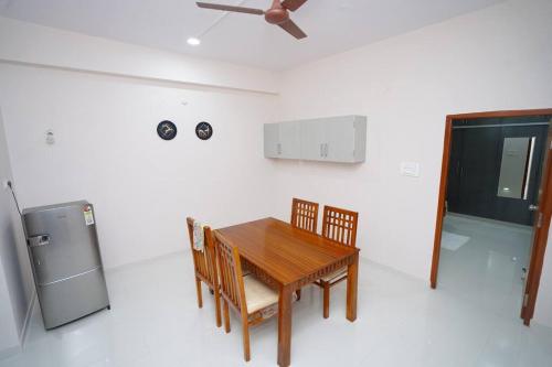 a kitchen with a table and chairs and a refrigerator at Chez Moi -II - 2BHK, Near US Embassy, Gachibowli in Hyderabad