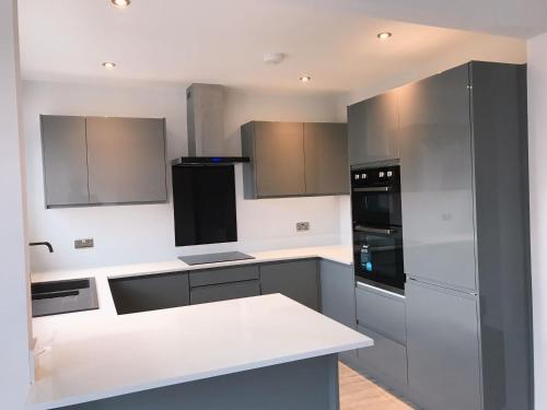 eine Küche mit grauen und weißen Schränken und Geräten in der Unterkunft Modern 3 Bed home in Grantham in Grantham