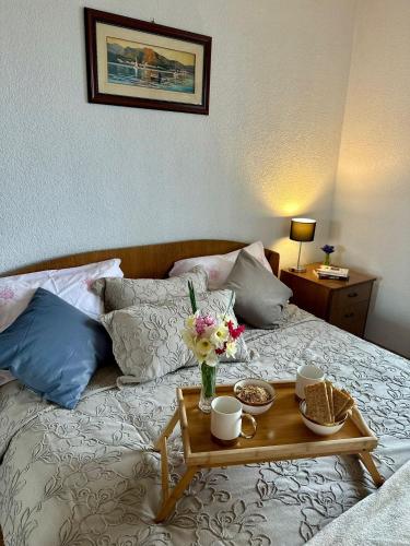 a bed with a table with a vase of flowers on it at Stan na dan Kej Una in Bosanska Dubica