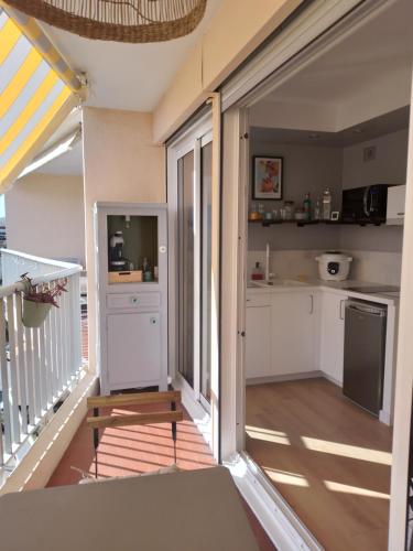 Il comprend une cuisine avec des placards blancs et un balcon. dans l'établissement Le studio 51, à Saint-Raphaël