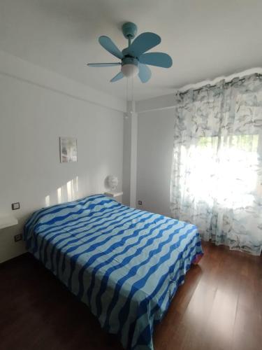 Schlafzimmer mit einem blauen und weißen Bett und einem Deckenventilator in der Unterkunft Piso luminoso en Madrid Rio in Madrid