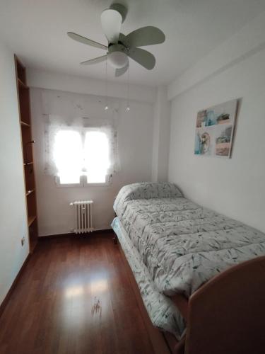 Un dormitorio con una cama y un ventilador de techo. en Piso luminoso en Madrid Rio, en Madrid