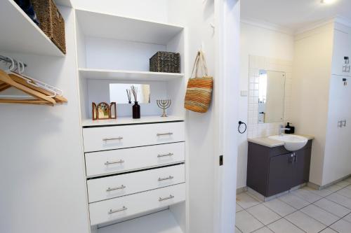 a bathroom with white cabinets and a sink at Beautiful spacious city apartment with views out to the Arafura Sea in Darwin