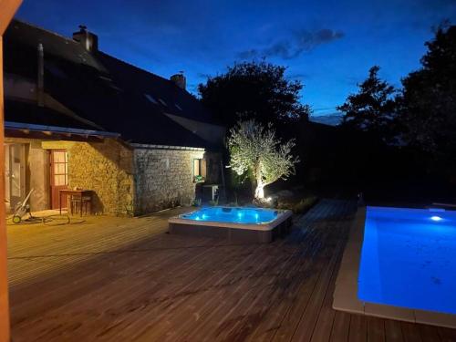 une arrière-cour avec une piscine la nuit dans l'établissement Maison avec piscine et jacuzzi en Briere, à Saint-Lyphard