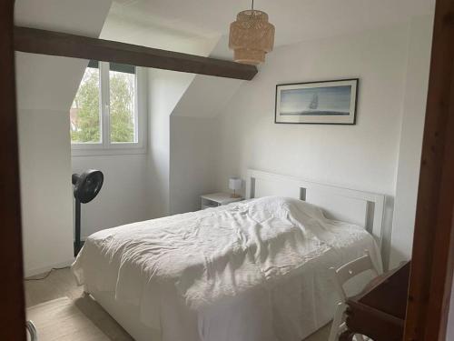 Habitación blanca con cama y ventana en Maison avec piscine et jacuzzi en Briere, en Saint-Lyphard