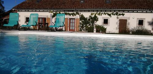 a swimming pool with blue chairs and a house at La Vieille Gorce Gîtes in the Vienne in Asnois