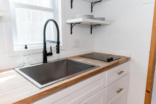 uma cozinha com um lavatório de aço inoxidável e uma janela em Pine Creek Tiny House em Amherst