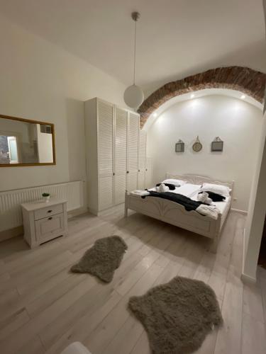 a white bedroom with a bed and two rugs at Luxury Ultra Central in Sibiu