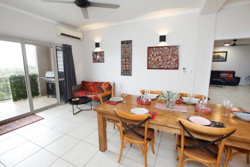 een eetkamer met een houten tafel en stoelen bij Beautiful spacious city apartment with views out to the Arafura Sea in Darwin