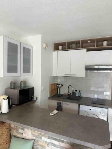 une cuisine avec des armoires blanches et un comptoir dans l'établissement Appt en RDJ à 2 min de la plage, à Antibes