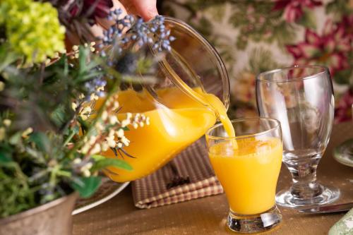 een persoon die een sinaasappelsap in een glas giet bij The Oakwood Inn Okoboji in Okoboji