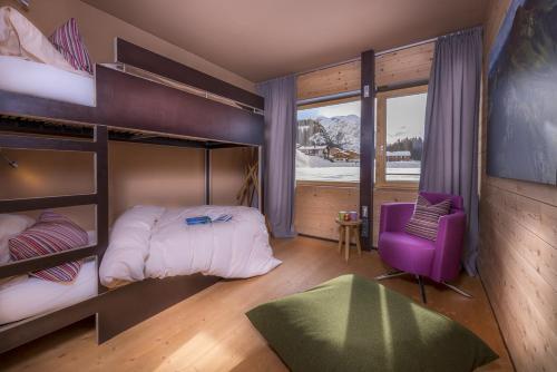 レッヒにあるDesign Chalets Lechのベッドルーム1室(二段ベッド2台、紫色の椅子付)