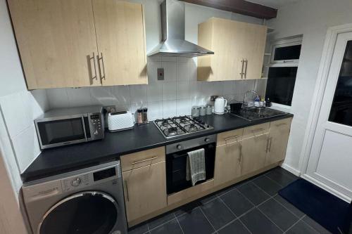 a kitchen with a stove and a microwave at 2-bedroom house in Cheltenham town centre in Cheltenham