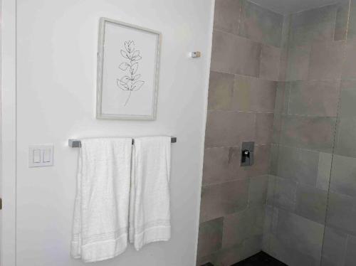 ein Badezimmer mit zwei weißen Handtüchern und einer Dusche in der Unterkunft Modern, chic & cozy 2br 2ba apartment in Wynwood in Miami