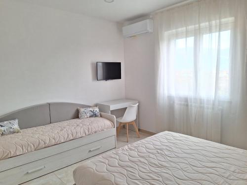 een witte slaapkamer met een bed en een televisie bij Mimì Luxury Apartment in Pompei