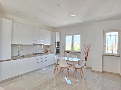 een keuken met witte kasten en een tafel en stoelen bij Mimì Luxury Apartment in Pompei