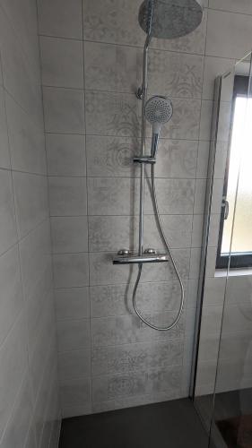 une douche avec pommeau de douche dans une salle de bain dans l'établissement Les Gîtes du Grain Clos, à Conteville