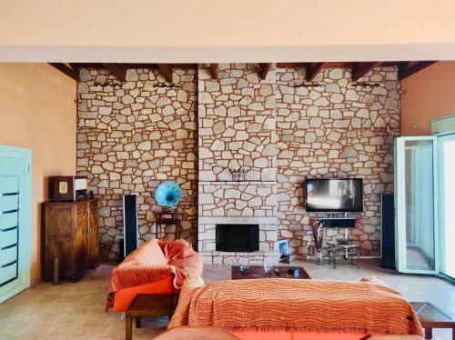 1 dormitorio con pared de piedra, 1 cama y TV en Villa Cymothoe, en Chiliadou