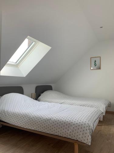2 camas en una habitación con ventana en ENHOTI, en Plouër-sur-Rance